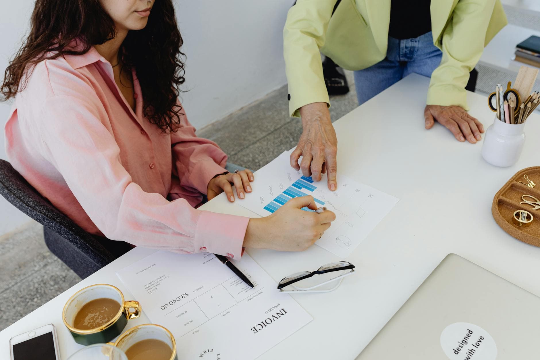 Two people reviewing a bar chart and an invoice at a desk
