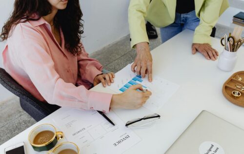 Two colleagues work together on financial graphs, promoting teamwork in a modern office setting.